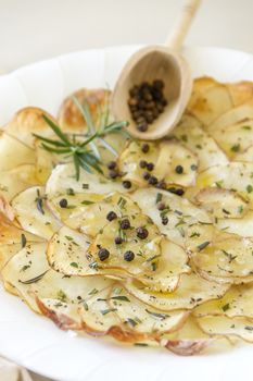 Delicious crispy baked potato chips with rosemary and pepper corns ready to serve.