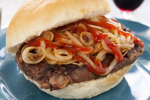 Freshly prepared fillet steak burger with fried onions and ketchup