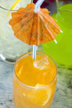 Delicious quenching orange drink with ice and a cocktail umbrella.