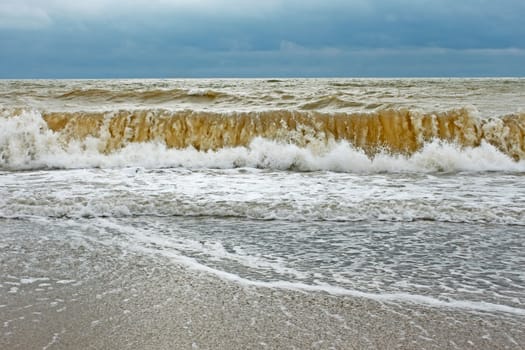 Big stormy wave with sand contaminated water directed ashore