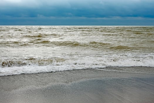 Sea coast after the storm with contaminated water with sand dredged from the seabed