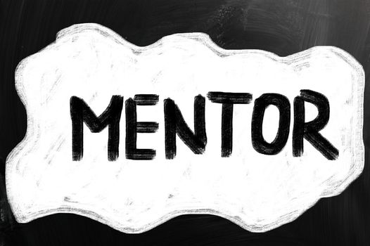 "Mentor" handwritten with white chalk on a blackboard.