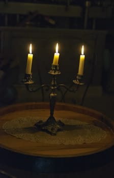 Three old candles over a candlestick over a barrell