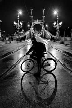 Cyclist in front of Liberty Bridge of Budapest at night