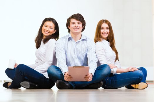 portrait of a group of young people sitting on the floor, man and two attractive women