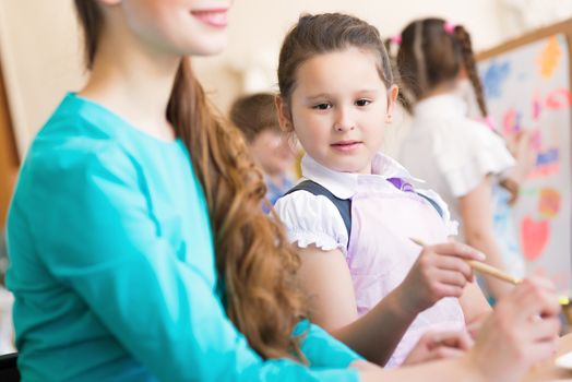 girl in the school, near the teacher and other children