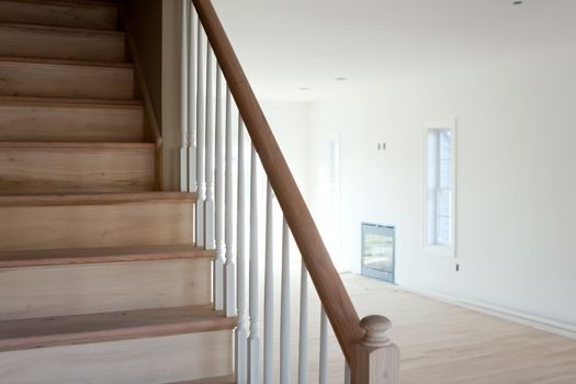 New home construction interior room with unfinished wood floors stairway and railings. Electrical and hvac connections are also partially unfinished.