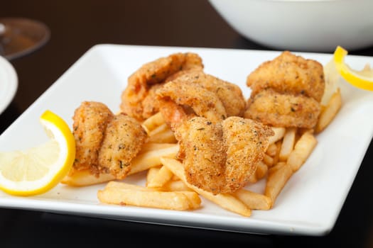 Fried shrimp and french fries plate garnished with lemon.