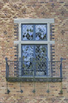 Tudor Style Windows with Rod Iron Scrollwork Metal Balcony on Exterior Brick Wall