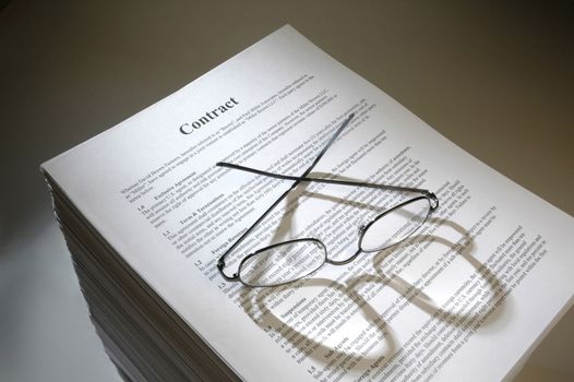 A pile of papers representing a multi-page legal contract. (The generic contract text was created for this photograph. The names shown are ficticious. There is no copyright infringement.)