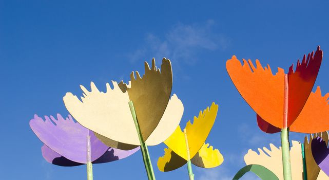 colorful stylized design decor tulips cut from plywood wood board against blue sky background.