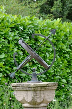sun dial with hedge in bacground