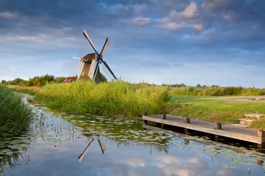 Dutch windmill reflected in river with water lilies