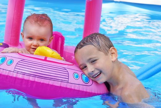 A big brother poses next to his little sister in the heat of the summer while swimming in the refreshing pool.