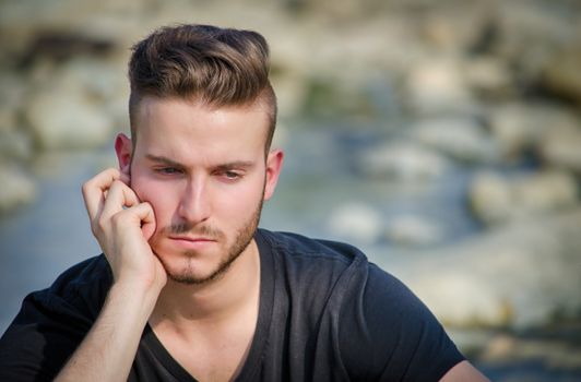 Portrait of sad, worried or depressed young man outdoors thinking