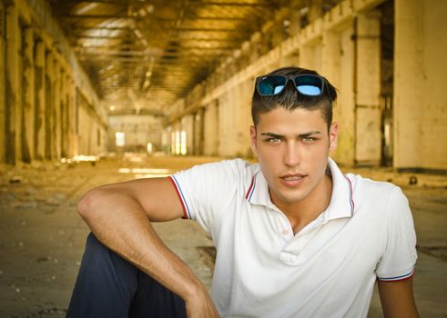 Handsome young man in abandoned, empty warehouse or old factory