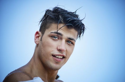 Portrait of attractive young man smiling outdoors with blue sky behind