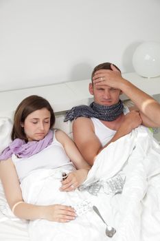 Portrait of a young couple in bed together as they both sick