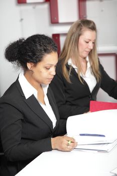 Two businesswomen discussing over file at office desk