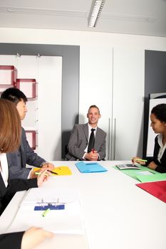 Group of business people listening to colleague addressing office meeting smiling