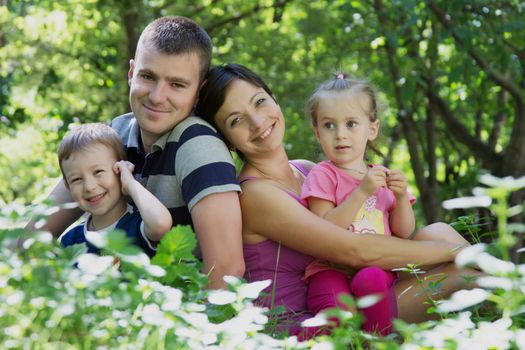 Happy family with two children sitting in park