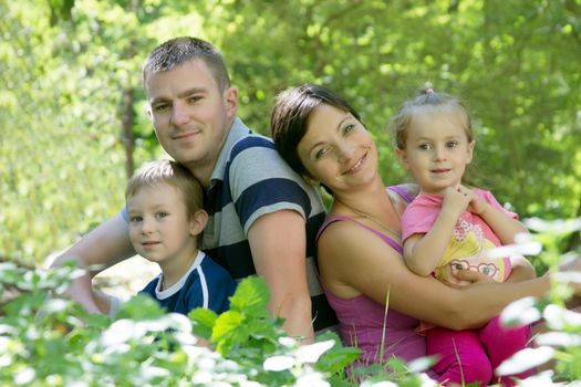 Happy family with two children sitting in grass