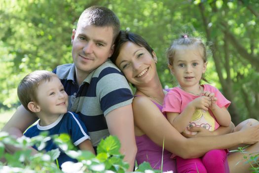 Happy family with two children sitting in the grass