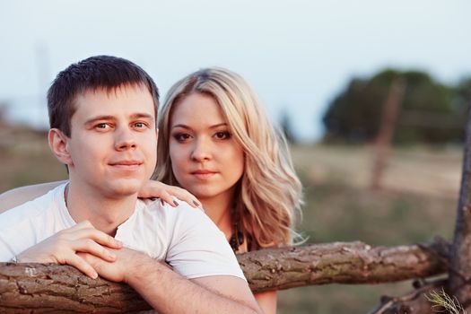 Young couple at sunset near a wooden fence