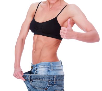 woman shows her weight loss by wearing an old jeans, isolated on white background