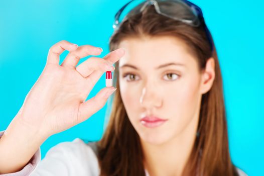 Young woman looking at the red pill, focus on pill