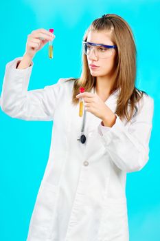 Young female doctor looking at the chemical tubes, focus on tube