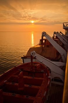 Sunset wtih lifeboats on a ship in the foreground