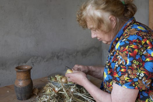 The old woman cuts an onions at itself in the house