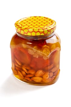 Bank of honey with the candied fruit and nuts on a white background