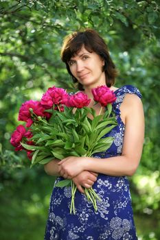 The woman of average years with flowers in a garden