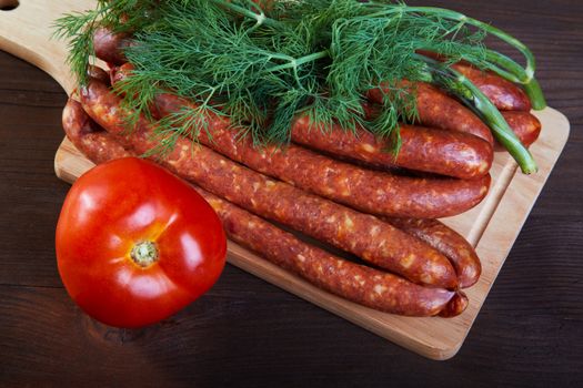 Sausage fennel and a tomato on an old wooden table