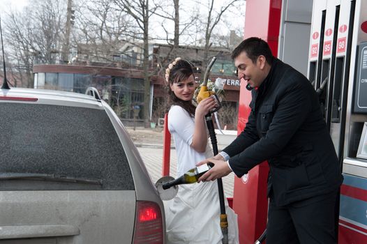 bride and groom fill the car with petrol and champagne