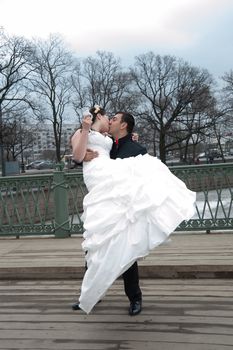 groom holds his bride in his arms and kisses