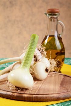 Onion and garlic with an olive oil bottle on a kitchen table