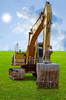 Track-type loader excavator machine on green grass field