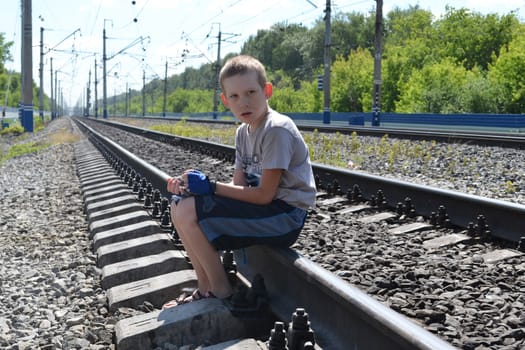 the sad boy sits on rails