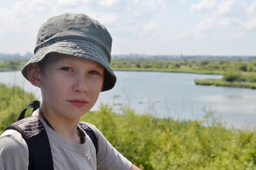 Portrait of the boy in a hat against the river