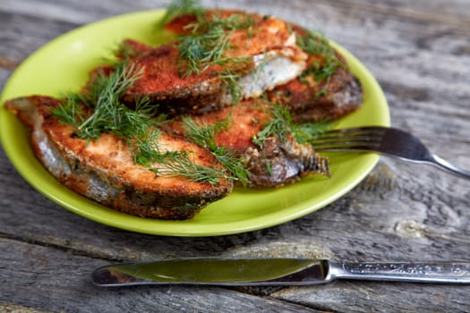 Plate with fried fish on a wooden table