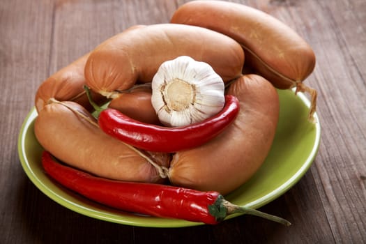 Sausages with spices and vegetables on an old wooden table