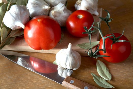 Tomatoes garlic and bay leaf branches on a kitchen table