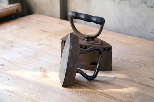 Two old irons on a table in beams of the coming sun