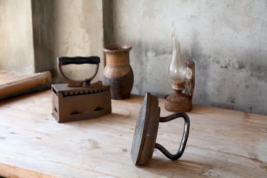 The old iron, oil lamp and jug on a wooden table