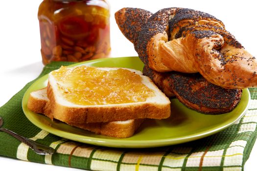 Pieces of bread with jam and rolls on a kitchen table