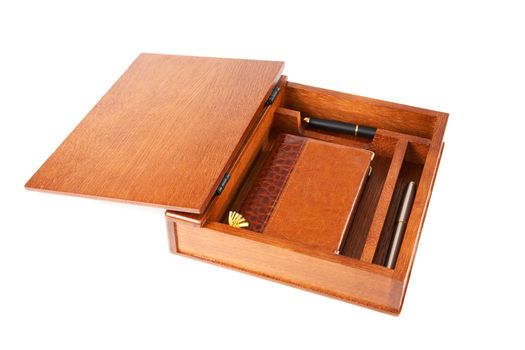 Wooden casket with  notebook and pens on a white background