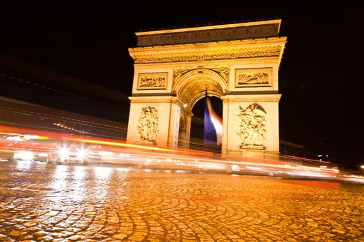 The Arc de Triomphe in Paris illuminated at night. 

